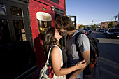 A young couple kisses on a sunny afternoon outside local Irish Pub, Brian Boru, in Portland, ME.