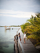 THATCH CAYE, BELIZE. A couple enjoy the boardwalk at a small caye in Belize.