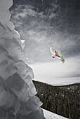 Side angle view of a snowboarder spinning off a jump in the Colorado backcountry.
