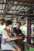 DOMINICAL, COSTA RICA. A woman and a man sit at a bar drinking beer.