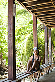 DRAKE BAY, OSO PENINSULA, COSTA RICA. A woman sits on a bench wearing her snorkeling gear with a thick jungle behind her.