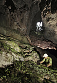 A British male cave explorers examines the rare plant life over 500m into this cave called Green Cave, Gunung Mulu National Park, Sarawak, Borneo.