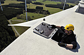 A technician climbs out of a hatch on the nacelle of a wind turbine in Germany.