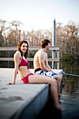 Wakulla Springs State Park, Florida, USA. Two teenagers sit on the edge of a dock at dusk in a state park with their feet in the water.