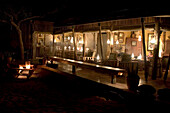 People preparing dinner and relaxing by oil lamps at the Wolwedans Dune camp at night by while on Safari in the Namib Rand Nature Reserve in Namibia.