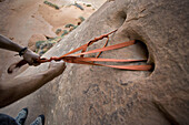 Setting up a rappel from natural holes in the rock in a canyon in Arches National Park, Utah.