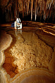 Cave explorer Syria Lejau looks into a very pretty Gour Pool. The floor of which is covered with 'dog tooth' crystals. The edges of the pool are very fragile because they overhang so much. These pools were discovered on this latest expedition and are loca
