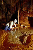 Cave explorer Syria Lejau looks into a very pretty Gour Pool. The floor of which is covered with 'dog tooth' crystals. The edges of the pool are very fragile because they overhang so much. These pools were discovered on this latest expedition and are loca