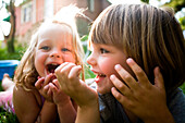 Two small kids smile for the camera in the garden. releasecode: sloan_cordon, kieran_reilly
