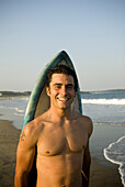 Man leaning against surfboard, Scarborough Beach, Maine, New England.  releasecode: rausher