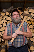 Man with axe and large pile of cut wood stockpiled for upcoming winter season - Juan de Santa Ana.