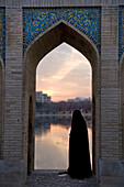 Esfahan, Iran - February, 2008: Iranian woman in one of the many arches on Khaju Bridge in Esfahan, Iran which spans the Zayandeh River and is a popular hangout for locals in the evening.