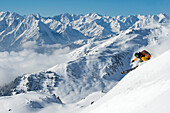 Skifahrer auf Steilflanke, dahinter der Alpenhauptkamm, Kaltenbach, Zillertal, Österreich