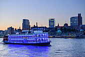 Beleuchtetes Schaufelradschiff Louisiana Star fährt auf der Elbe, St. Pauli-Landungsbrücken im Hintergrund, Hamburg, Deutschland