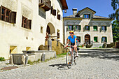 Radfahrerin fährt über Kopfsteinpflaster, Guarda, Unterengadin, Engadin, Kanton Graubünden, Schweiz