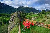 Cyclist resting on a bench, Ardez in background, Lower Engadin, Canton of Graubuenden, Switzerland