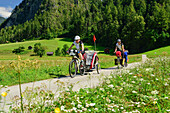 Two cyclists with child trailer riding along Inn cycle route, Zams, Tyrol, Austria