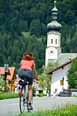 Radfahrerin fährt auf einer Landstraße, Erl, Tirol, Österreich