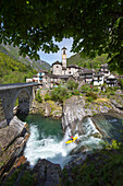 Kajakfahrer fährt über Stufe vor Dorfkulisse, Lavertezzo, Verzasca, Tessin, Schweiz