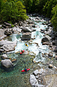 Three kayaker in a rapid on the crystal clear waters of the Verzasca, Ticino, Switzerland