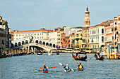 Three kayakers on the Canal Grande in front of the Rialto bridge, Venice, Italy