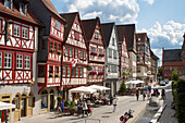 Menschen sitzen draußen vor Cafes und Restaurants der prächtigen Fachwerkhäuser in der Altstadt, Ochsenfurt, Franken, Bayern, Deutschland