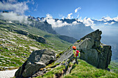 Frau beim Wandern steht vor Felsnadel, Sentiero Roma, Bergell, Lombardei, Italien