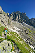 Woman hiking towards rocky mountain, Sentiero Roma, Bergell range, Lombardy, Italy
