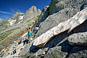 Frau beim Wandern steigt über Felsplatten, Sentiero Roma, Bergell, Lombardei, Italien