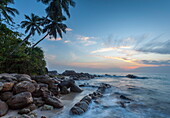 Sunrise at a secluded lagoon with rocks and palm trees framing the view, Tangalle, Sri Lanka, Indian Ocean, Asia