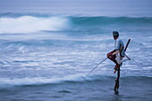 Stilt fishing, a stilt fisherman in the waves at Midigama near Weligama, South Coast, Sri Lanka, Indian Ocean, Asia