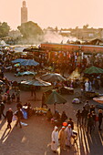 Evening light on the busy square of Place Jemaa el-Fna with the minaret of the Koutoubia Mosque in the distance, UNESCO World Heritage Site, Marrakech, Morocco, North Africa, Africa