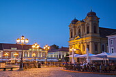 Roman Catholic Cathedral and outdoor cafes in Piata Unirii at dusk, Timisoara, Banat, Romania, Europe