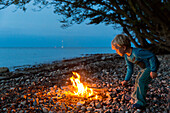 Junge am Lagerfeuer am Ostseestrand, Naesgaard, Falster, Dänemark