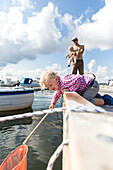 Father and children (1-4 years) on a jetty in harbor, Guldborg, Falster, Denmark
