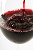 Red wine pouring into glass, close-up