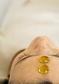 Woman reclining with two glass pebbles on forehead, close-up