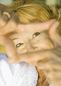 Senior woman looking at camera through finger frame