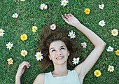 Woman lying on grass with flowers scattered around head