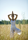 Woman doing yoga pose in field