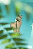Young woman in pool, topless, rear view