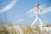 Young woman standing on dune, exercising