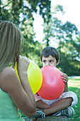 Boy and mother blowing up balloons