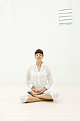 Frau sitzt in meditativer Haltung, Augen geschlossen