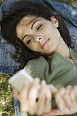 Woman lying on ground text messaging