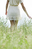 Young woman walking through tall grass, cropped