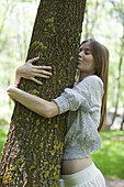 Young woman hugging and kissing tree