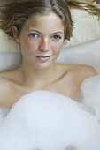 Young woman relaxing in bubble bath, portrait