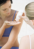Woman squeezing sunscreen into friend's hand