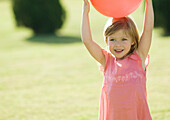 Little girl holding ball on head